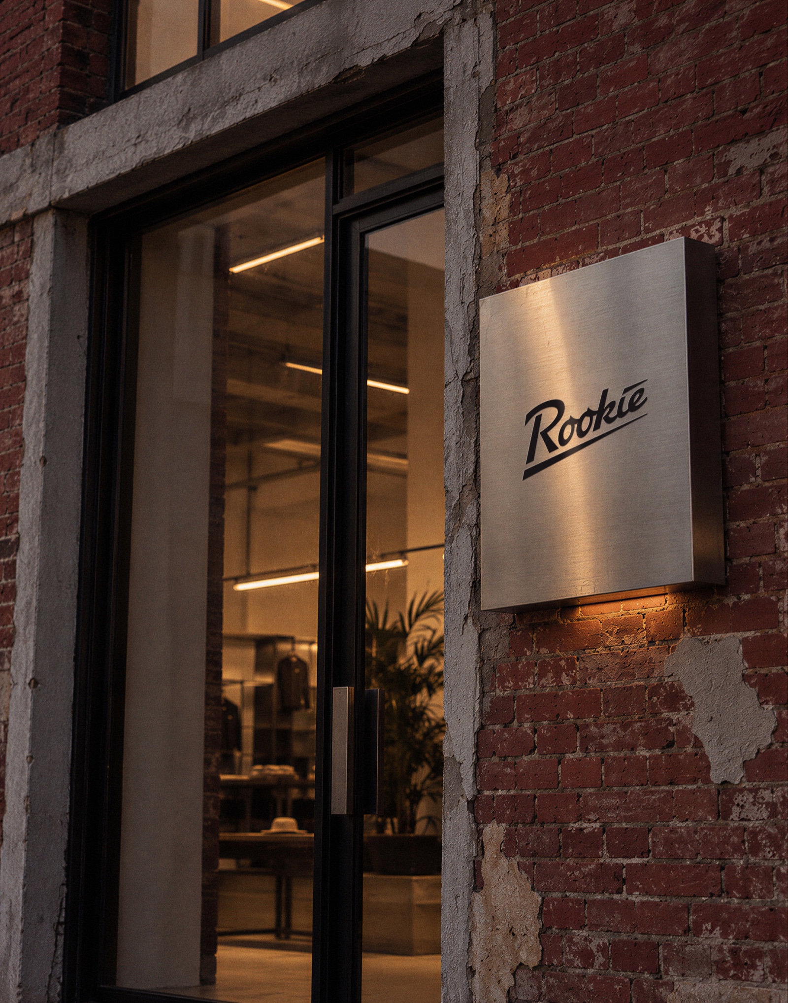 Brushed steel Rookie sign beside a store door on a brick wall