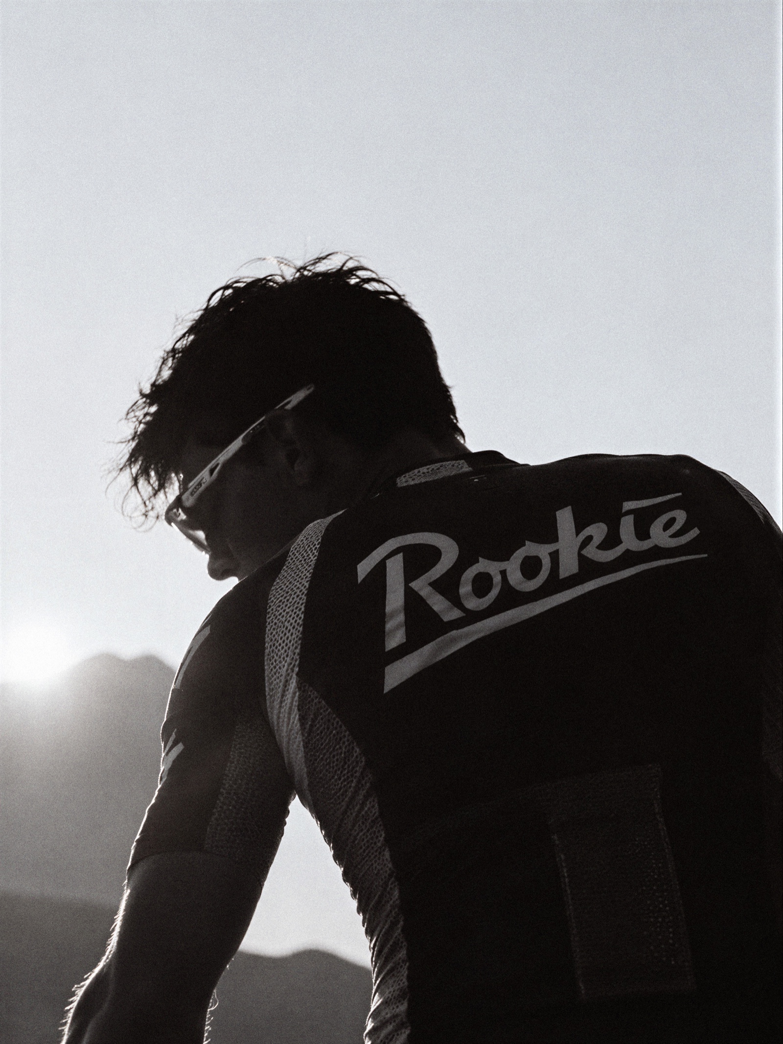 Cyclist from behind in a Rookie jersey against the sun