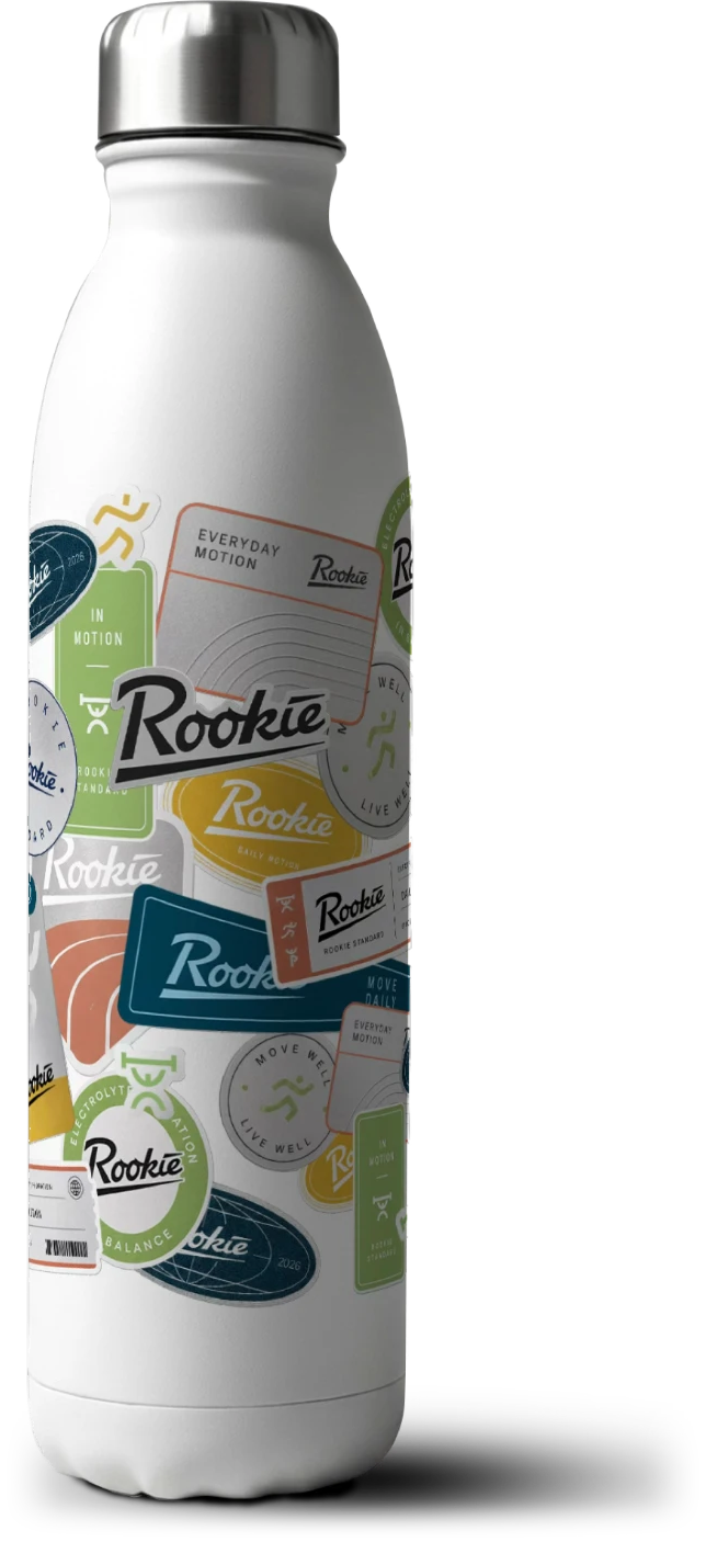 A white Rookie water bottle covered in stickers, with 'Leave your mark' rolling upward behind it on a grey wall